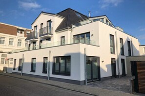 A modern two-story residential building with a balcony, large windows, and a flat roof. - Holiday apartment with 3 bedrooms (Norderney)