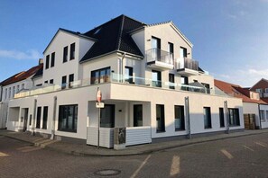 A two-story residential building with a balcony on the upper floor, a garage door, and a clear sky. - Holiday apartment with 3 bedrooms (Norderney)