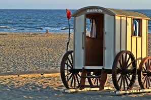 Eine Holzkonstruktion am Strand mit einem Schild, Rädern und einer Flagge.
