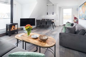 Ein modernes Wohnzimmer mit Kamin, Essbereich und einer Couch.