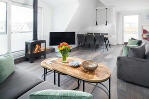 Ein modernes Wohnzimmer mit Kamin, Essbereich und einer Couch.