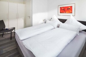 Ein Hotelzimmer mit einem Bett, einem Sessel, einem Schrank und einem gerahmten Bild an der Wand.