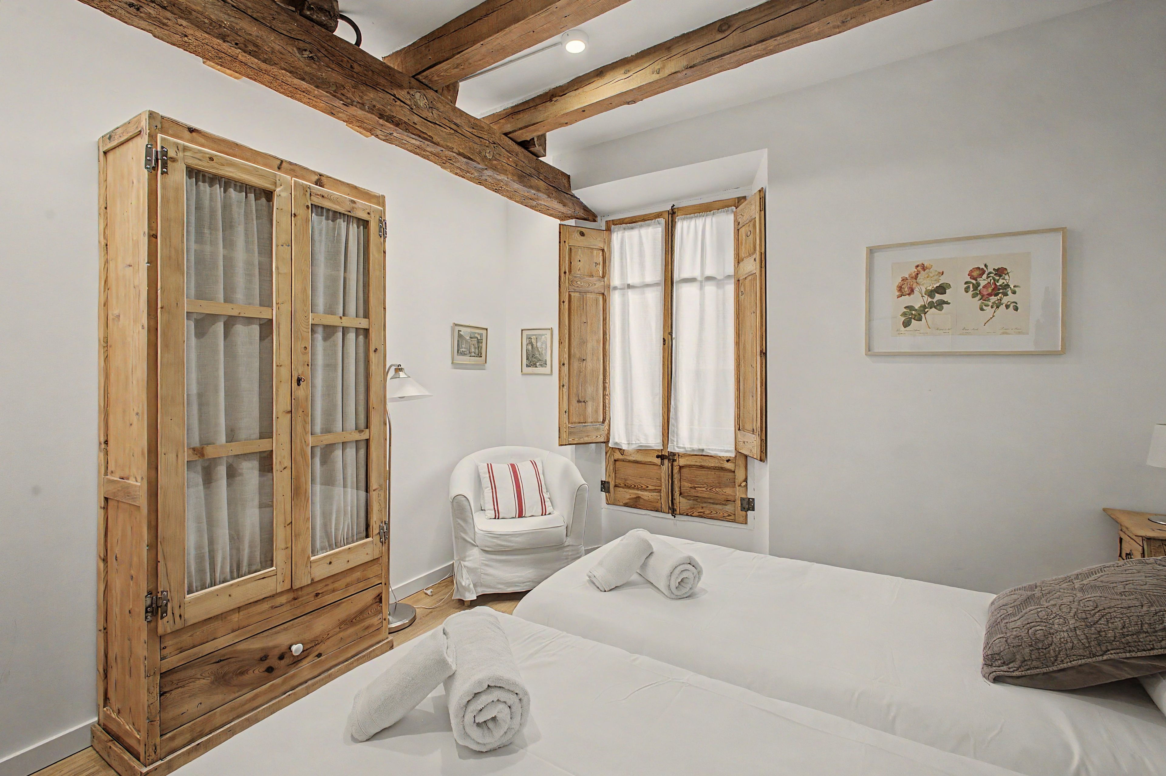 Een kamer met een bed, een stoel en een grote houten garderobe.