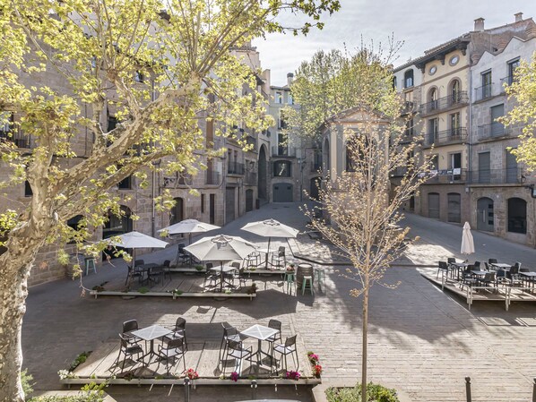 An outdoor café area with tables and chairs, surrounded by stone buildings with arches. - Apartment 'Pèndol' with Balcony, Wi-Fi and Air Conditioning (Solsona)