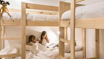 Tweepersoonsbed met witte lakens en een popje op het bovenste bed.