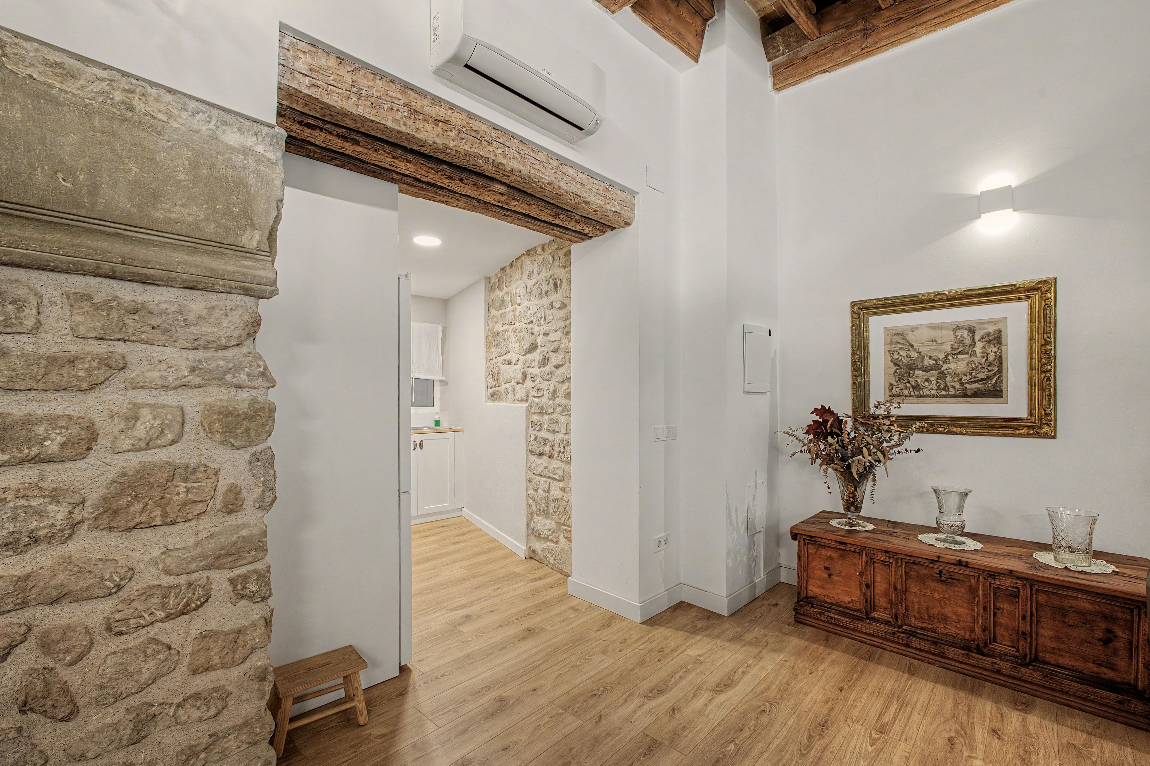 A room with a stone wall, wooden floor, a wooden cabinet, and a framed picture on the wall.