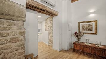 A room with a stone wall, wooden floor, a wooden cabinet, and a framed picture on the wall.
