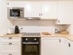 A modern kitchen with white cabinets, a built-in microwave, a coffee maker, and a toaster. - Apartment 'Pèndol' with Balcony, Wi-Fi and Air Conditioning (Solsona)