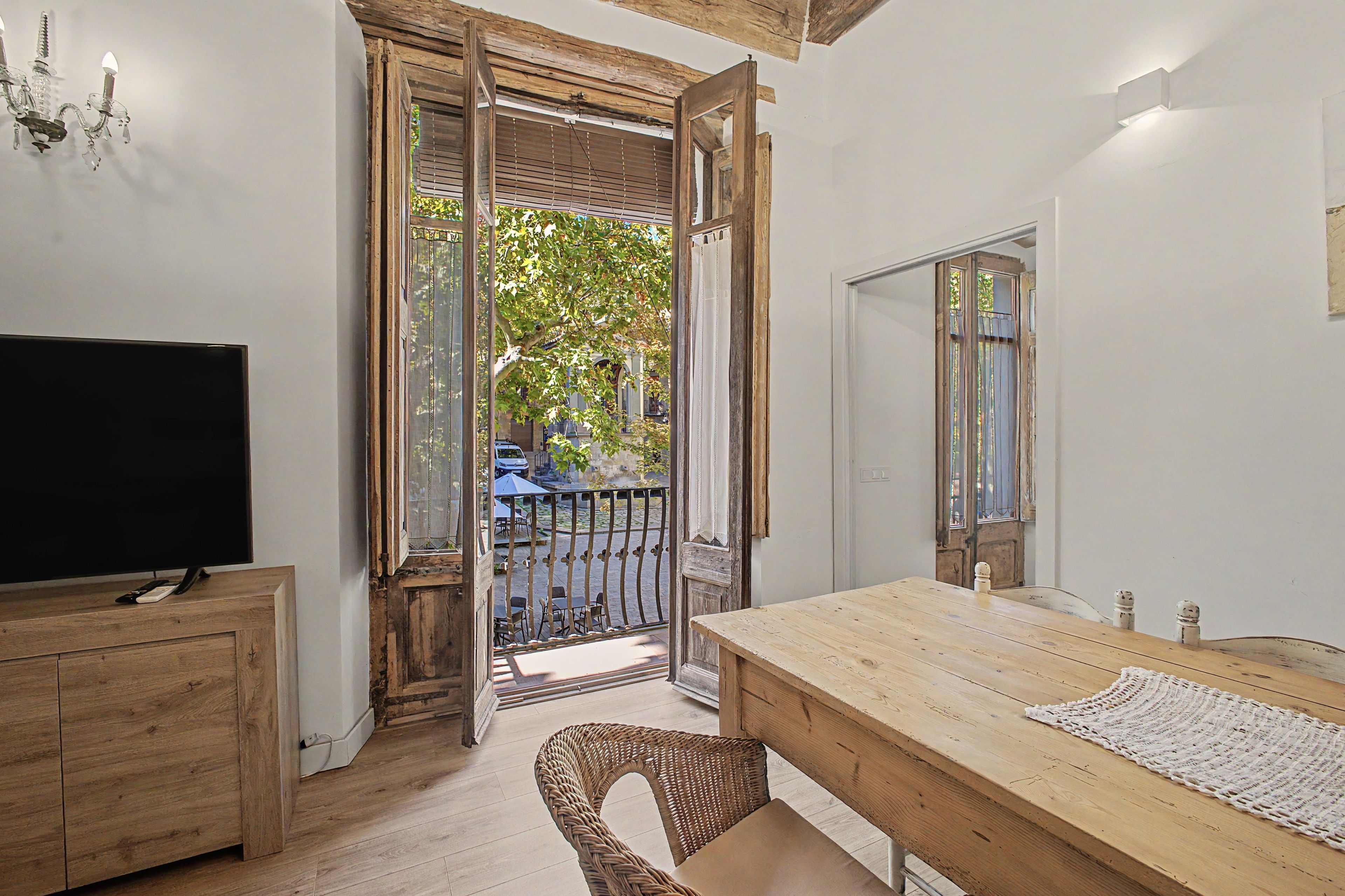 Une pièce avec une table en bois, un téléviseur et une chaise en osier.