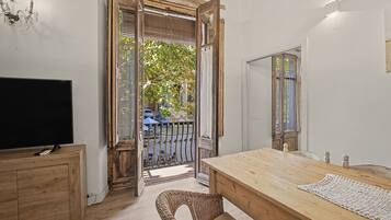 Une pièce avec une table en bois, un téléviseur et une chaise en osier.