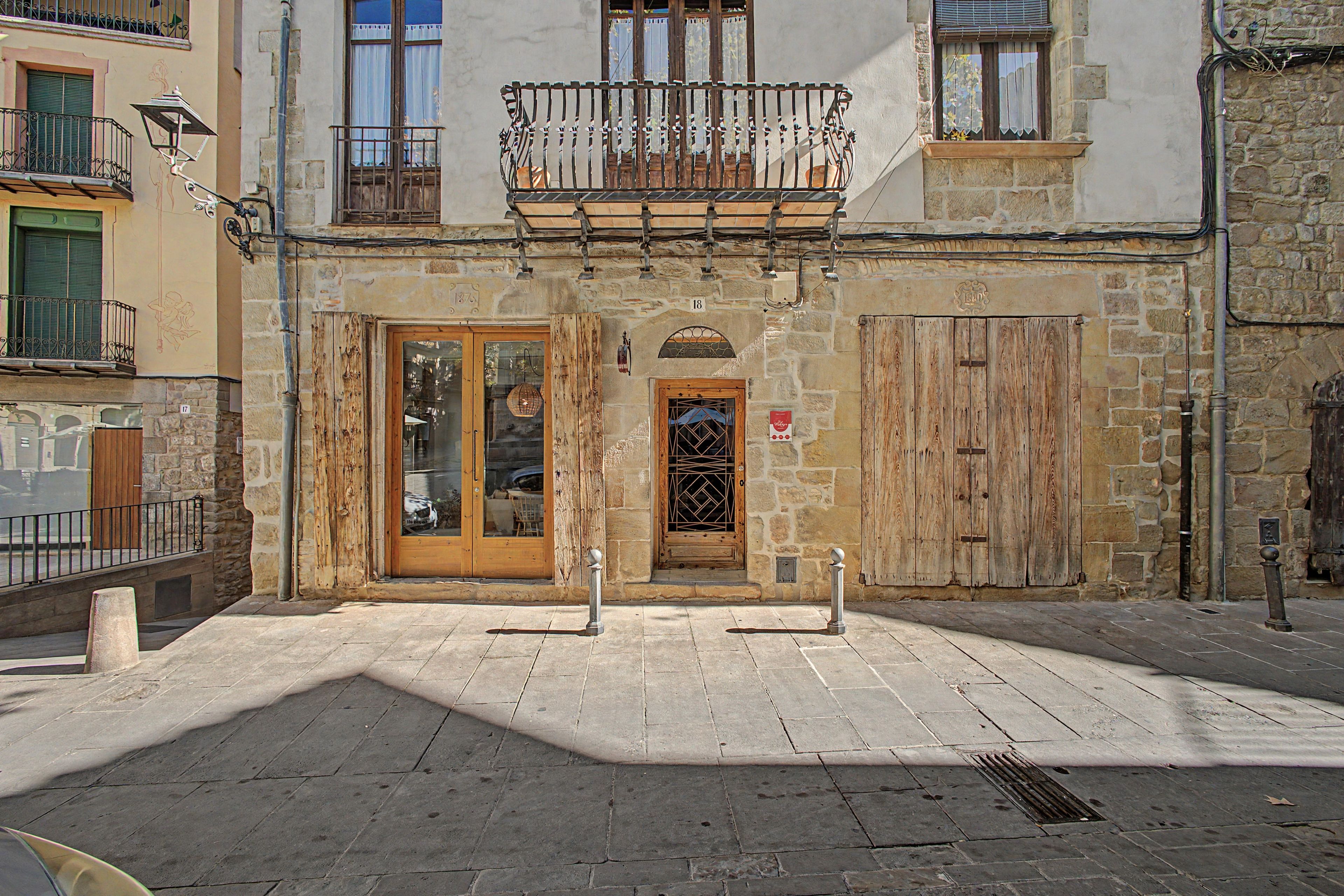A building with a stone facade, a wooden door, and a balcony with metal railings.