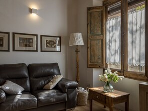Un salon avec un canapé en cuir, une lampe, un vase de fleurs et des tableaux encadrés accrochés au mur.