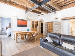A spacious living area with a wooden dining table, leather sofa, and a chandelier. - Apartment 'Pèndol' with Balcony, Wi-Fi and Air Conditioning (Solsona)