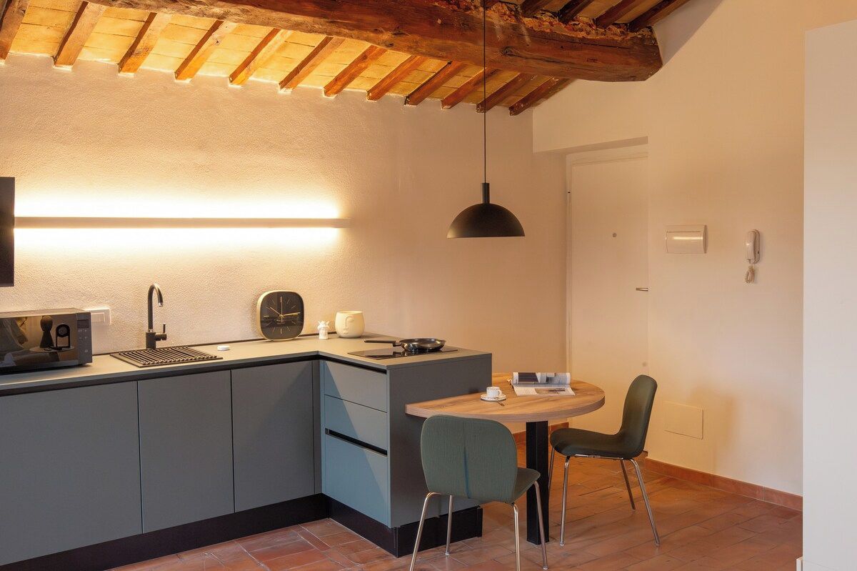 A compact kitchen with a built-in microwave, a sink, and a dining area with a table and chairs.