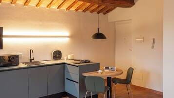 A compact kitchen with a built-in microwave, a sink, and a dining area with a table and chairs.