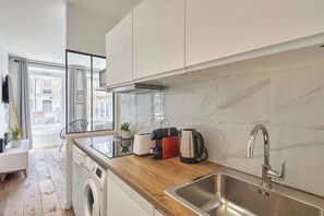 Eine moderne Küche mit Einbauwaschmaschine, Edelstahlspüle und Fenster mit Blick auf eine Skyline.