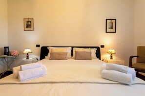 Une chambre d’hôtel avec un grand lit, deux lampes de chevet, une chaise et deux tableaux encadrés au mur.