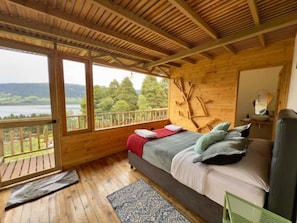 Eine Holzhütte mit einem Bett, Blick ins Freie und einem Balkon.