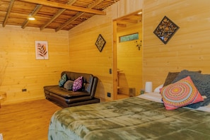 A wooden cabin room with a bed, a leather sofa, and a small table. - Neusa Hills Glamping (Tausa)