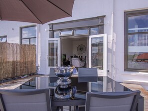 An outdoor dining area with a glass table, chairs, and a large umbrella. - Do43 "t Groentje 9A (Domburg)
