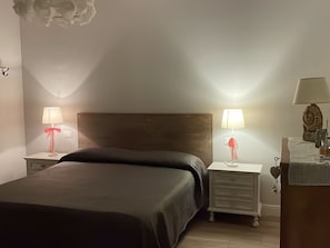 A hotel room with a bed, two bedside tables with lamps, a wooden headboard, and a nightstand with a lamp. - Sunflower Apartment (San Felice del Benaco)