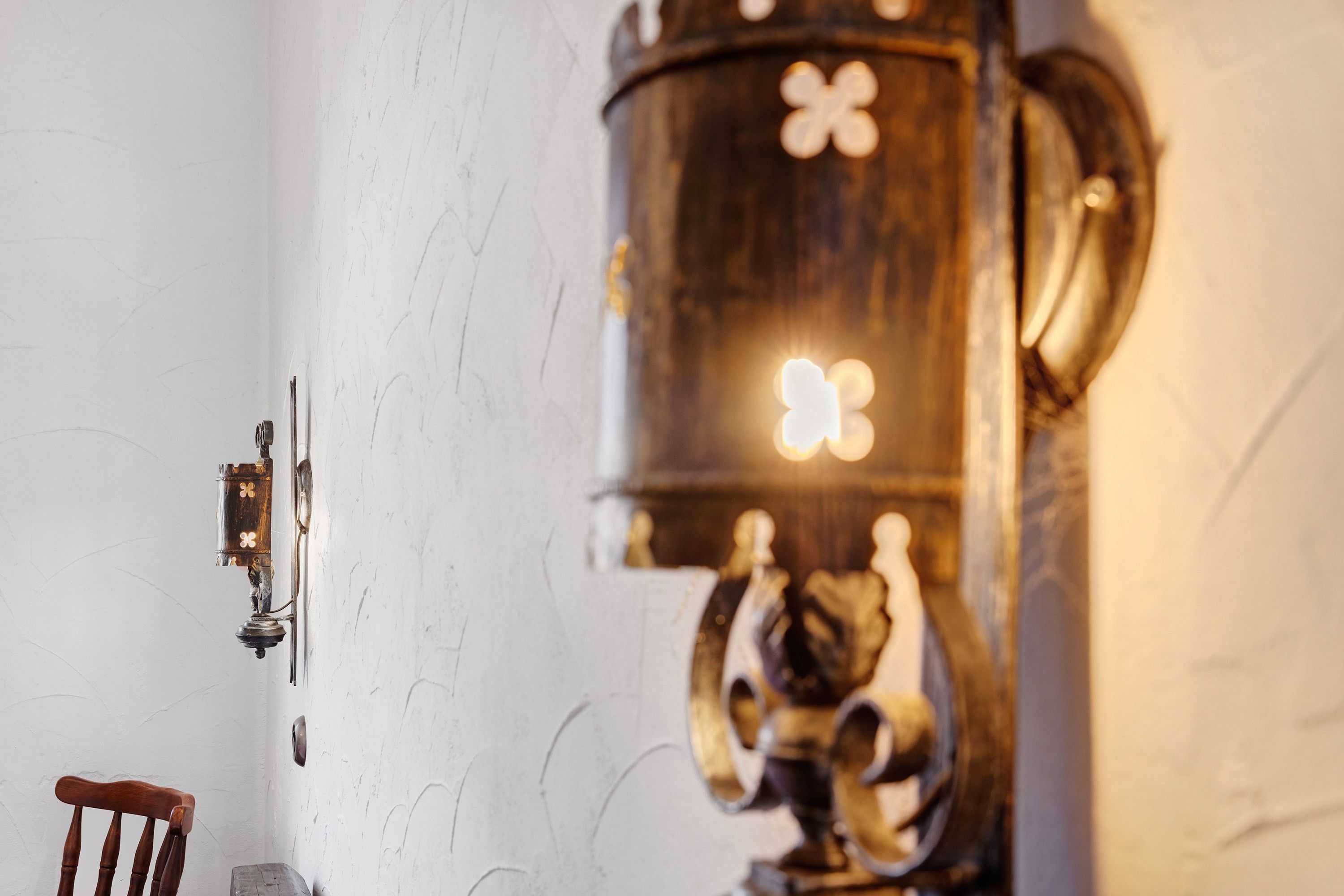 Un mur rustique avec une porte en bois et un luminaire mural doté d’un motif décoratif.