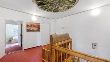 Ein Flur mit einer Holztret Treppe, einem roten Teppich, einer Tür und einer Decke mit dekorativer Gestaltung.
