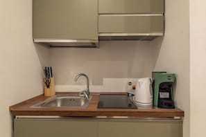 Eine Küche mit Spüle aus Edelstahl, einer Kaffeemaschine und einem Toaster auf der Arbeitsplatte.