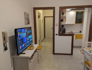A living room with a television, a kitchen area with a sink, and a hallway leading to another room. - Lake View Apt. w/ Wi-Fi & Parking in San Feliciano (San Feliciano)