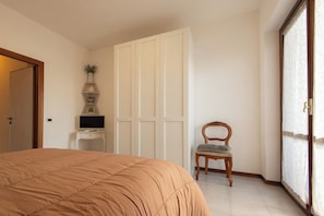 Une chambre à coucher avec un lit, une chaise, un téléviseur posé sur une petite table et une armoire.