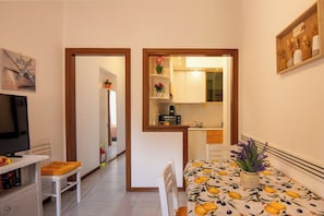 Un espace de vie compact comprenant un coin repas, une kitchenette et un téléviseur.