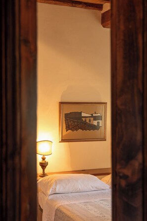 Ein Schlafzimmer mit einem Bett, einer Nachttischlampe und einem gerahmten Bild an der Wand.