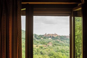 A view through a window with curtains, revealing a landscape with buildings and greenery. - Villa Missiano Unità Cassiopea con Piscina (Panicale)