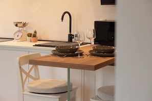 A kitchen with a wooden table, two bowls, a wine glass, a scale, and a sink.