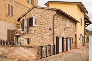 A stone building with a brick facade, a small porch, and a metal gate. - Romantic Suite w/ Private Terrace Near Assisi (Rivotorto)