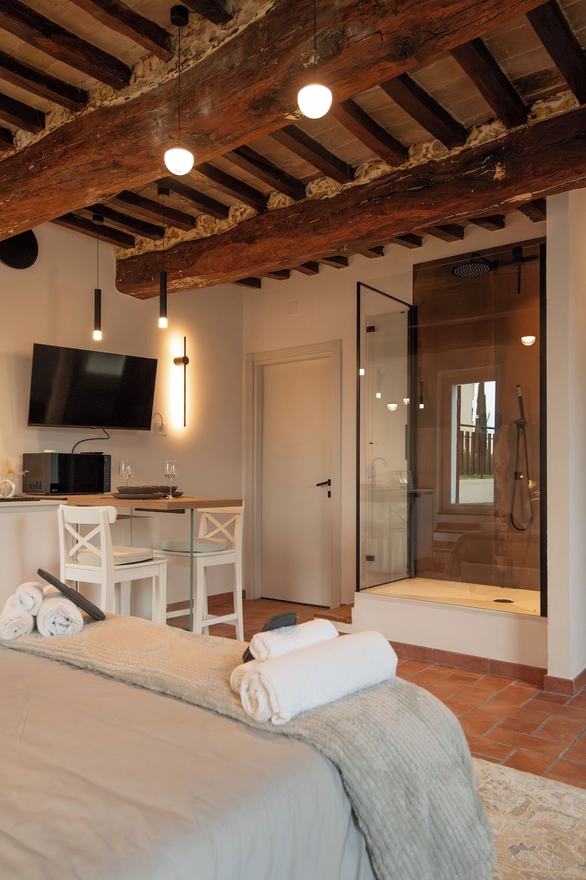 Una camera da letto con un letto, una scrivania con TV, un box doccia e una porta vetrata che dà su un balcone.