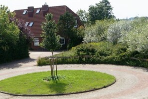 Een woonhuis met een geplaveid opritje, een gazon en een houten omheining.