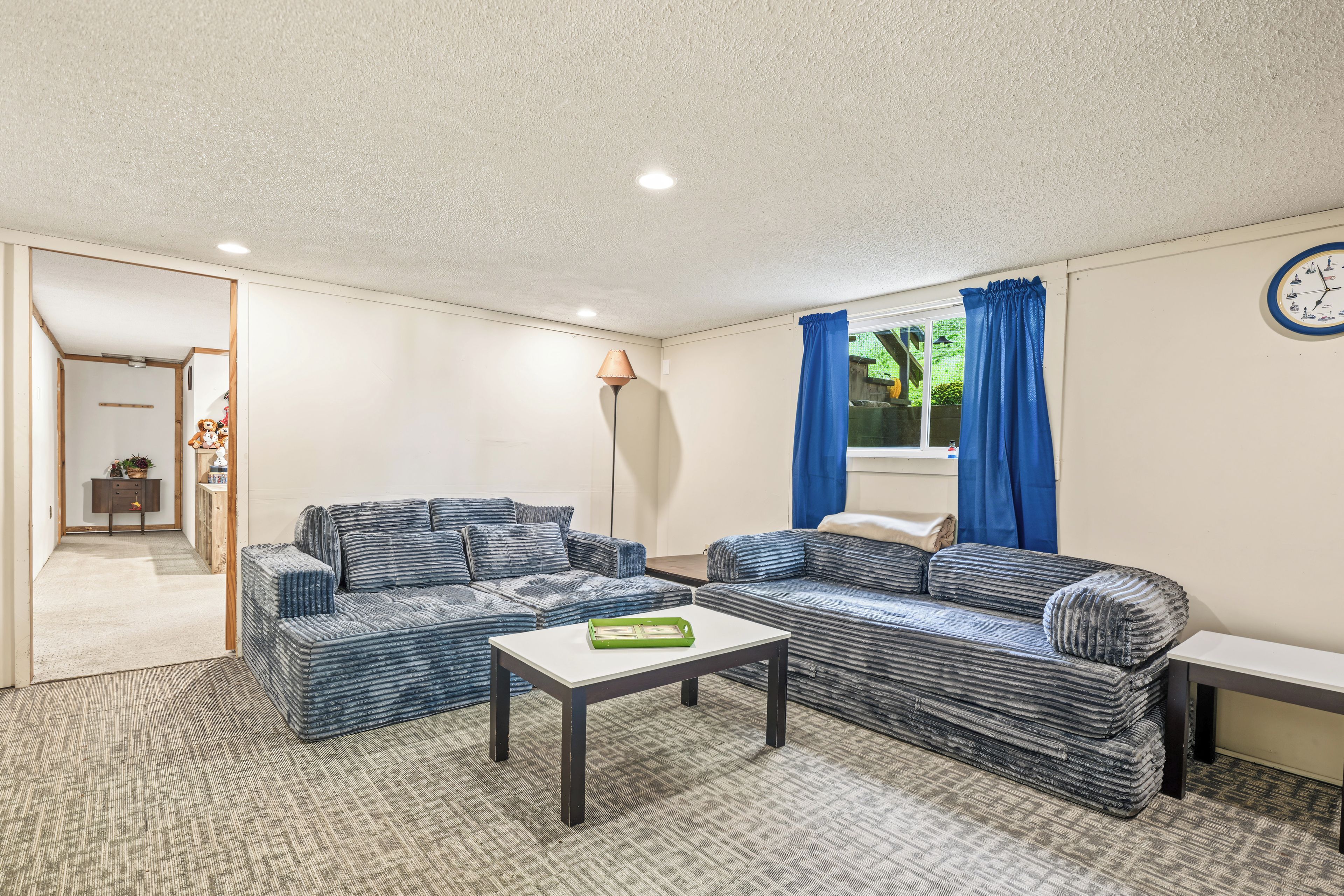 A furnished living room with a sofa set, a coffee table, and a clock on the wall.