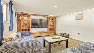 A cozy living room with a flat-screen TV, wooden bookshelves, a sofa, and a coffee table.