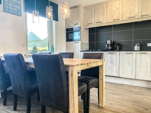 A modern kitchen with wooden cabinets, a black tiled backsplash, and pendant lighting. - Ok38 Holiday Home With dog (Grijpskerke)
