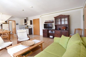 A living room with a green sofa, wooden coffee table, and a television on a wooden cabinet. - Holiday apartment with 1 bedroom (Ostseebad Prerow)