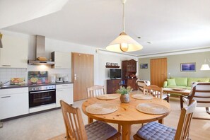 Eine moderne Küche mit Essbereich, Holzschränken und einem Fernseher.