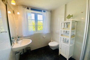 Ein Badezimmer mit Waschbecken, Toilette und Fenster.