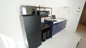 Eine kompakte Küche mit Kühlschrank, Mikrowelle, Toaster und Kaffeemaschine auf der Arbeitsplatte.