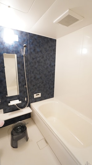 Ein modernes Badezimmer mit einer Badewanne, einer Dusche, einem WC und einem Waschtisch mit Spiegel.