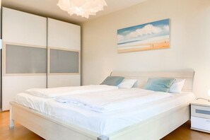 Ein Schlafzimmer mit einem Bett, einem Nachttisch, einem Wandbild und einer Deckenleuchte.