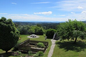 A landscaped garden with a paved path, a seating area, and a view of distant hills. - Holiday home with 3 bedrooms (St. Stefan ob Stainz)