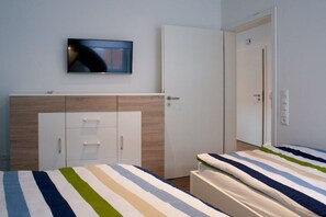 Une chambre à coucher avec un lit, un téléviseur fixé au mur, une armoire et une porte.