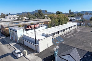 Un motel con letrero, zona de estacionamiento y vistas del paisaje circundante.