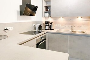 A modern kitchen with a built-in oven, a coffee maker, and a sink. - Timmare IV Little Crab (Timmendorfer Strand)
